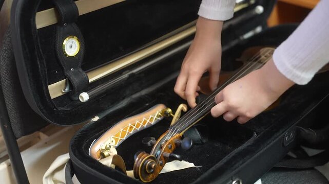 A girl puts her violin in a trunk at a music school