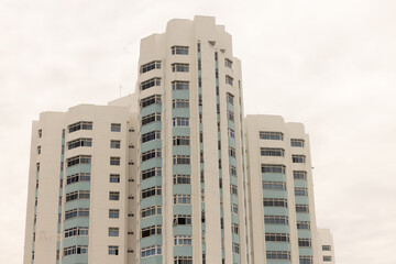 Multi storey residential apartment building with many windows and balconies isolated against bright white sky highlighting urban housing architecture, modern city living, and residential development © Anton