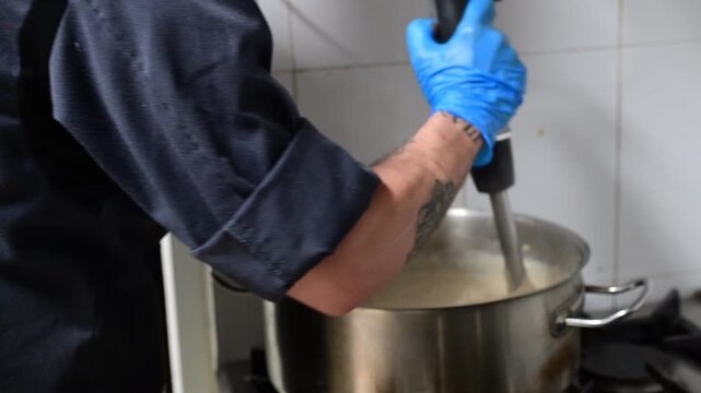 Chef preparing a bechamel sauce with a blender in a professional kitchen
