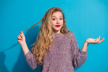 Young stylish woman with blonde hair wearing a purple sweater posing against a blue background