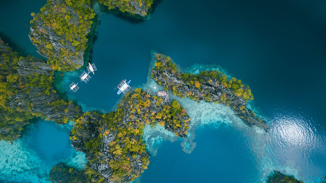 Aerial view of islands fringed with verdant foliage meet the turquoise waters, boats dotting the tranquil coves, creating a stunning contrast of nature's artistry, Palawan, Palawan, Philippines.