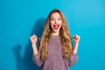 Young stylish woman with bright smile celebrating success against blue background