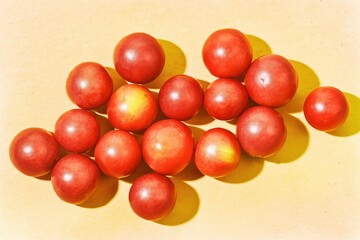 Obraz premium Red acerola cherries fruits are arranged on a light background showing natural shapes and shadows during daytime