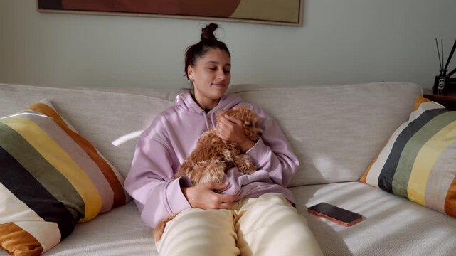 Casual woman in hoodie engaging with phone and petting dog