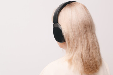 Woman with blonde hair wearing black wireless headphones and working on a laptop at a desk