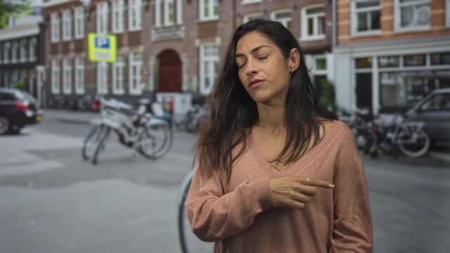 Woman points finger with hand toward street lined with parked bicycles and a brick building, puzzled expression and open palm gesture; doubt uncertainty.