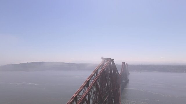 Aerial view of the Forth Bridge, a cantilever railway bridge with red steel contrasting with the calm blue waters, South Queensferry, United Kingdom.