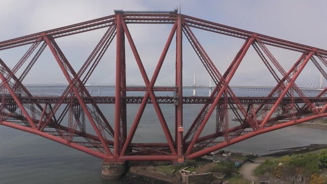 Aerial view of the red Forth Bridge over calm waters with two other bridges visible in the background, South Queensferry, United Kingdom.