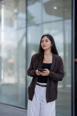 Fototapeta premium The determined businesswoman in a tailored suit holds a tablet while standing in a modern office, radiating poise, ambition, and a positive outlook on her professional journey.