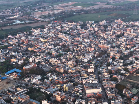 Aerial view of a densely populated rural town in india surrounded by green agricultural fields