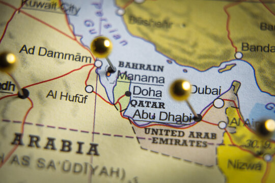 Close-up of a digital display showing Qatar on a geographical map with gold push pins marking Abu Dhabi, Dubai, and Doha