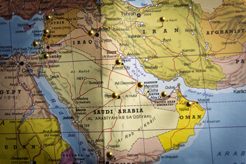 Fototapeta premium Middle East political map with gold push pins marking major cities in Iran, Iraq, and Saudi Arabia, geopolitical strategy and travel planning concept