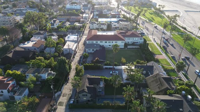 Neighborhood near E Ocean Blvd, Coronado Ave sits steps from Bluff Park with beach path, open shoreline visible beyond palm rows. Mixed roofing, bright stucco, soft coastal light, Long Beach, CA