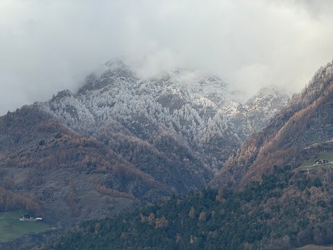 Panorama mountain landscape in Naturns in South Tyrol in autumn. In the background, the snow-covered mountains, shrouded in dense fog, no people.