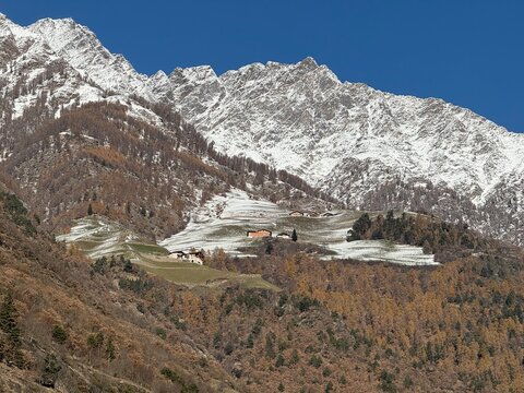 Panorama mountain landscape in Naturns in South Tyrol in autumn, in the background the snow-covered mountains, blue sky with clouds, no people
