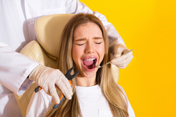 Young woman at dental checkup smiling during teeth whitening in clinic on yellow background