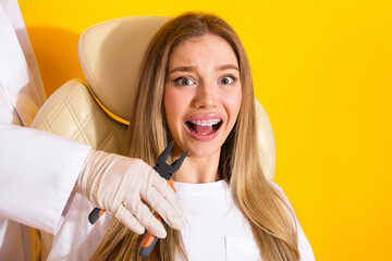 Young woman with braces smiling during dental appointment in bright yellow studio background