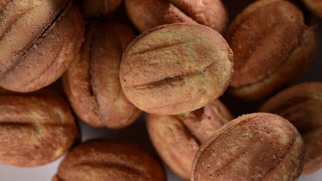 Macro close up of nut-shaped cookies filled with smooth condensed milk, slowly rotating on a turntable. Golden baked shells, detailed texture, and creamy filling highlighted in high definition. Sweet 