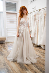 A portrait of a beautiful bride choosing a wedding dress in a store and trying it