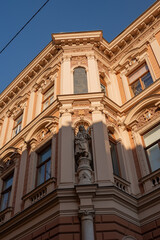Fototapeta premium Classic historic building yellow stone facade with neo classical ornaments close up. 