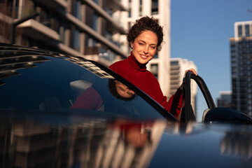 Woman smiling opening car door in city setting © Jelena