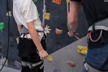 Climbing Instructor Checking Safety Harness and Rope for a Young Boy at Indoor Bouldering Gym
