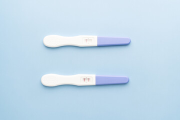 Pregnancy test with one and two stripes positive and negative results on blue background. Pregnancy test kit measure hCG levels in urine.