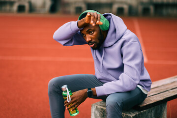Fototapeta premium Tired african athlete resting after workout on running track