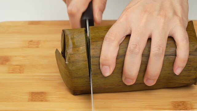 Slicing traditional Vietnamese Banh Tet with savory mung bean and pork fat