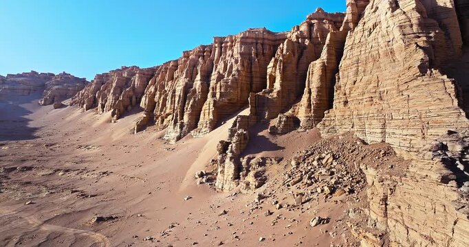 Panoramic view of yardang landforms and weathered rock formations in the Gobi Desert, Xinjiang, China. Vast arid desert under a clear blue sky.