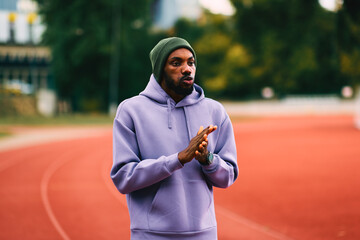 African athlete warming hands before workout on running track