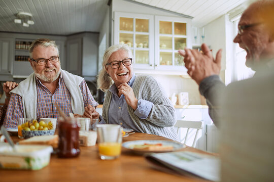 Happy senior friends laughing at breakfast in a cozy kitchen