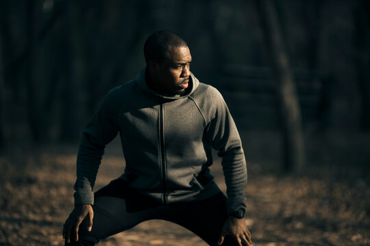 Athletic man stretching in a forest at sunrise