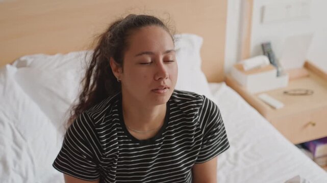 Restless hotel guest battling jetlag, young woman awake at night, checking phone, yawning and rubbing eyes, tossing duvet, city skyline visible through window, suitcase on floor, tense weary