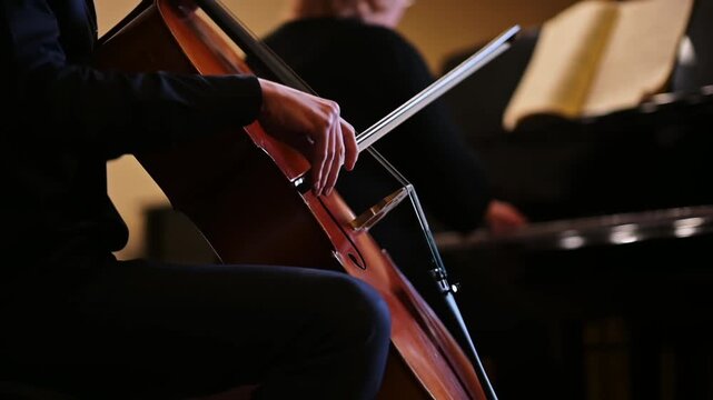 Cello player performing in a duet with a pianist during a classical concert.
