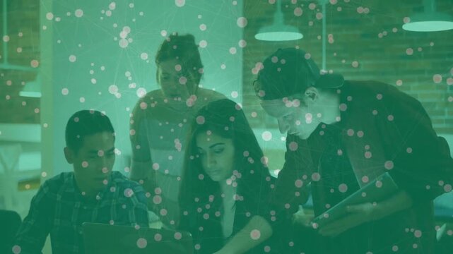 Team opening laptop, pointing at screen and jotting notes for project planning at office desk