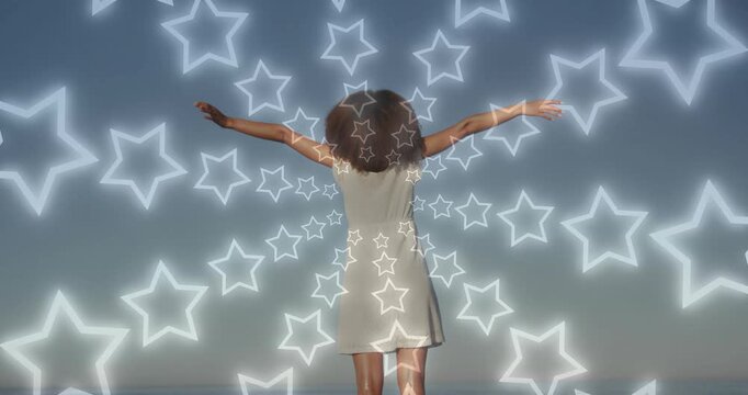 On beach woman raising arms outward upon star outlines radiating and cycling colors for wellness