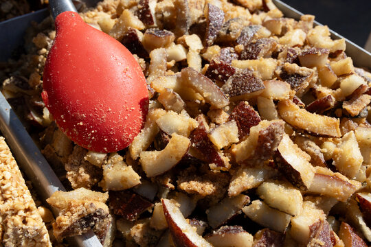 Sweet coconut candy, like cocada, fills a metal tray. Bright sun shines on sugary chunks. 