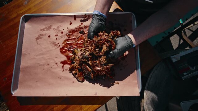 Full BBQ platter featuring brisket slices ribs sausage pickles red onion and sauce cup served on butcher paper on a wooden table