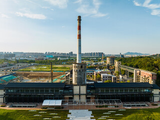 Obraz premium Industrial Heritage Factory with Striped Chimney and Urban Skyline