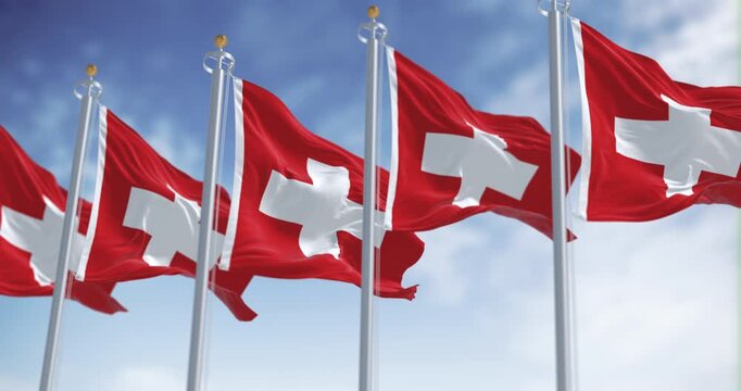 Swiss flags waving in the wind under a clear sky with white cross symbol