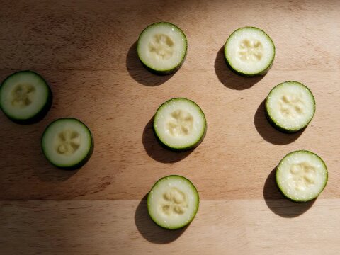 Zucchini Thin Slices. Minimalist Food Prep. Minimalist Food. thin zucchini slices being prepared, set in a minimalist wooden kitchen surface with negative space
