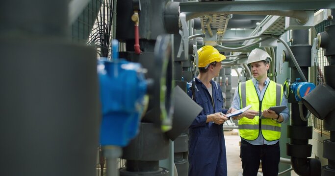 Professional engineer is inspecting industrial machinery valves in a modern plant, focusing on operational efficiency, quality control, and industrial safety compliance.