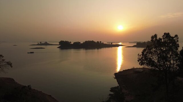 Aerial drone view of golden sunset over Kaptai Lake and green hills in Rangamati Bangladesh.