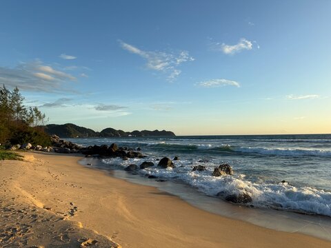 Sand beach among rocks on evening sunset. Lampuuk Beach near Aceh Besar at Hindian Ocean coast in Indonesia. Summer landscape.