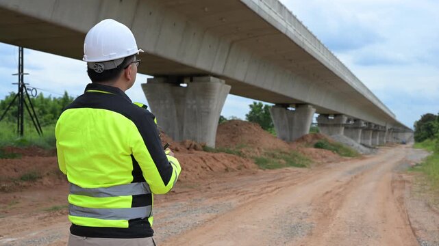 Professional civil engineer using digital tablet to inspect concrete bridge construction site. Infrastructure maintenance, structural engineering assessment and transportation safety development.