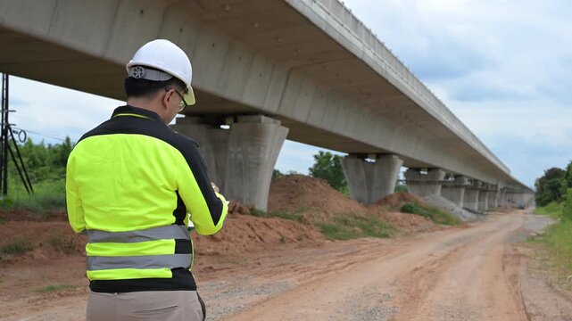 Professional civil engineer using digital tablet to inspect concrete bridge construction site. Infrastructure maintenance, structural engineering assessment and transportation safety development.