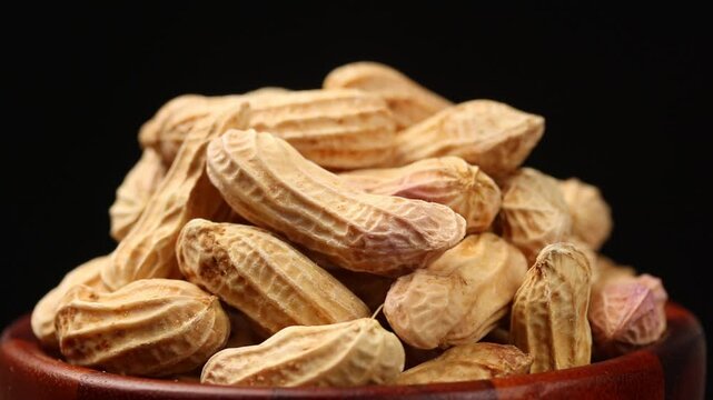 Pile of boiled whole peanuts in shell rotating slowly on black background