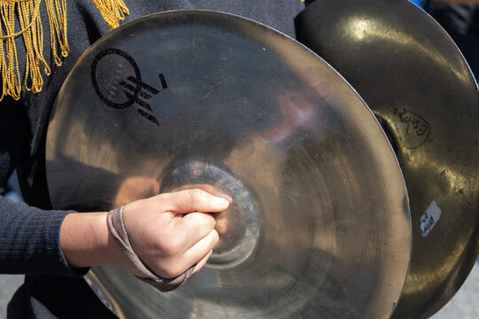 Close-up, high-angle view of a musician's hands holding brass cymbals. 
