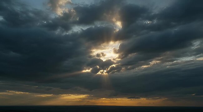 Dramatic sky with sunbeams breaking through dark storm clouds at sunset